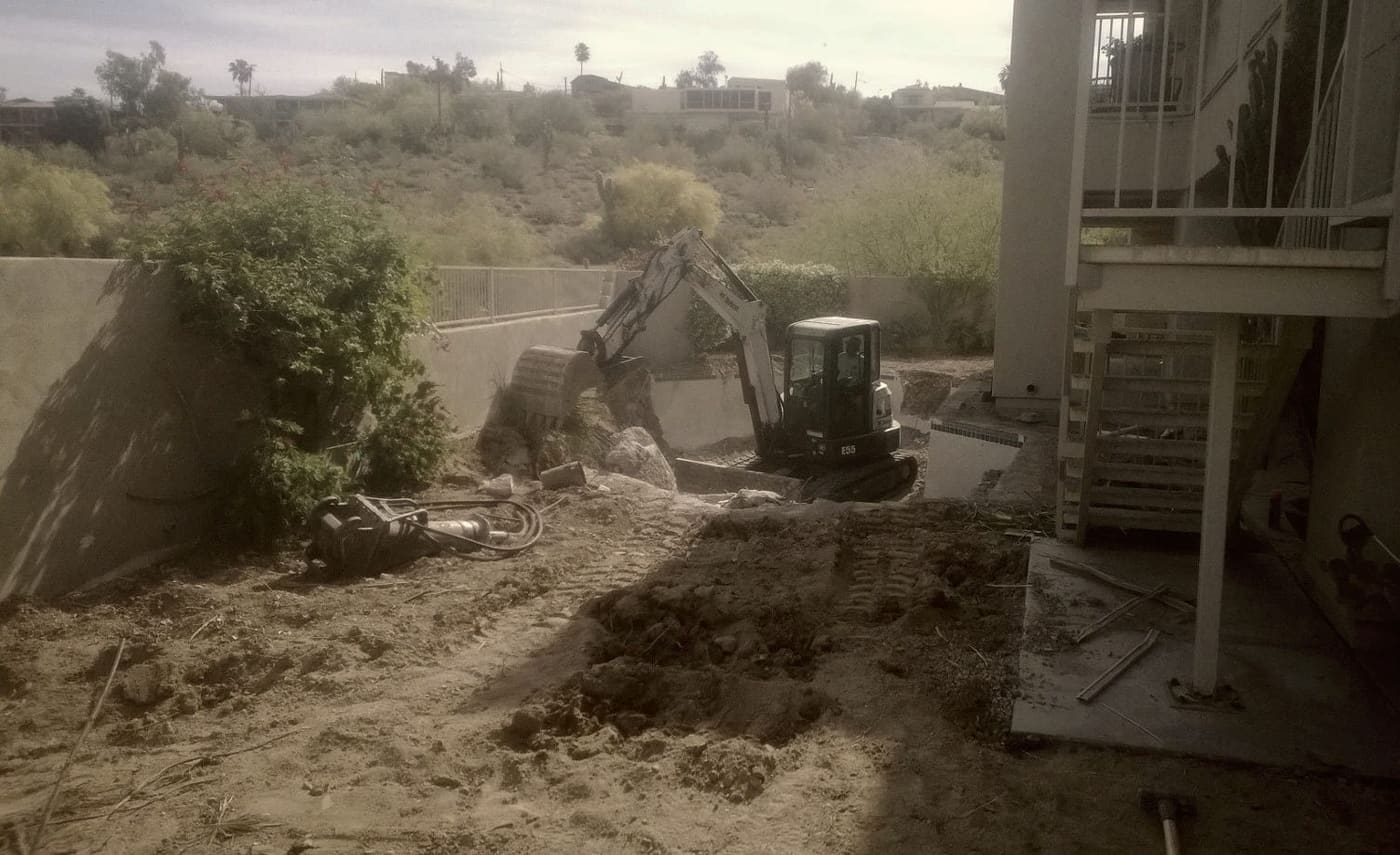 An excavator working tight against the side of a house.