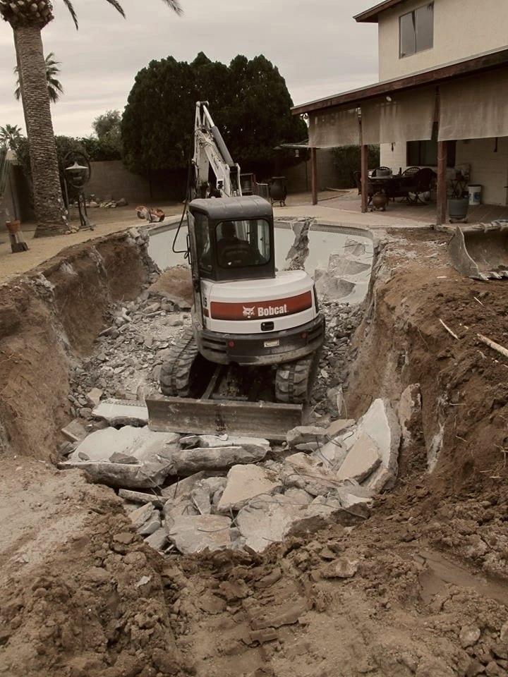 Breaking out a pool shell, rubble stacked where the water was.